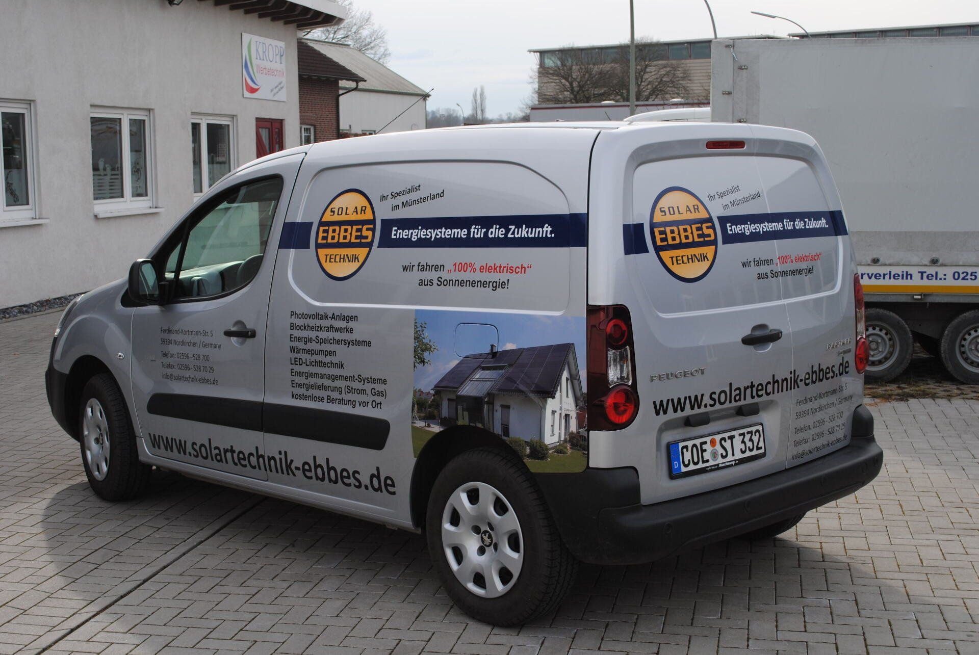 A white van is parked in front of a building