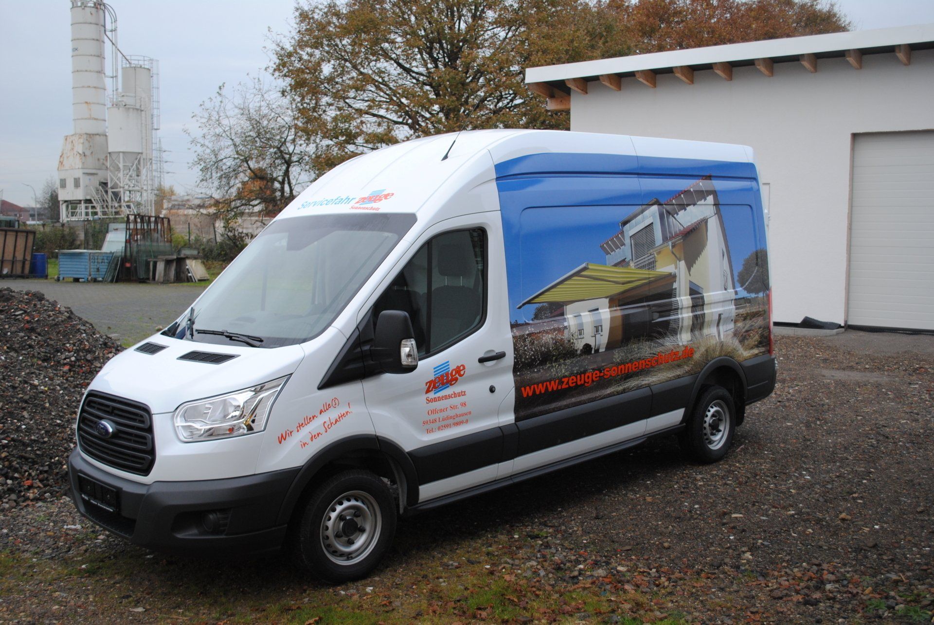 A white van with a picture of a house on the side is parked in front of a building.