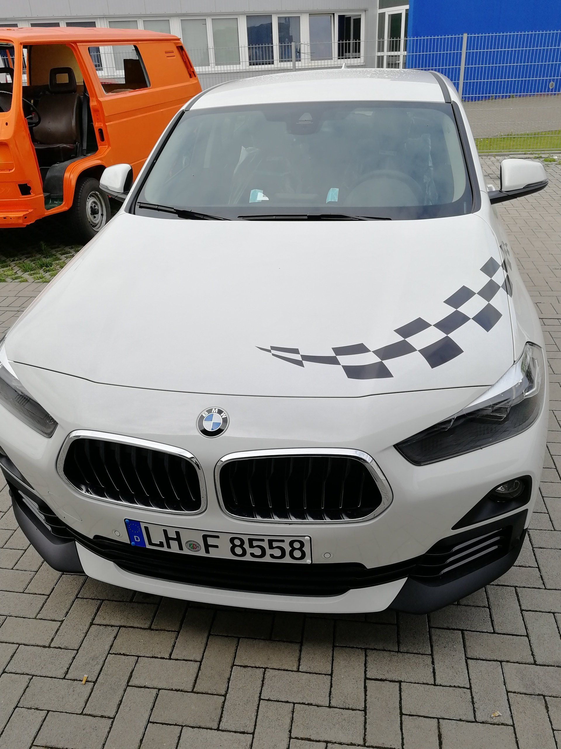A white bmw with a checkered pattern on the hood