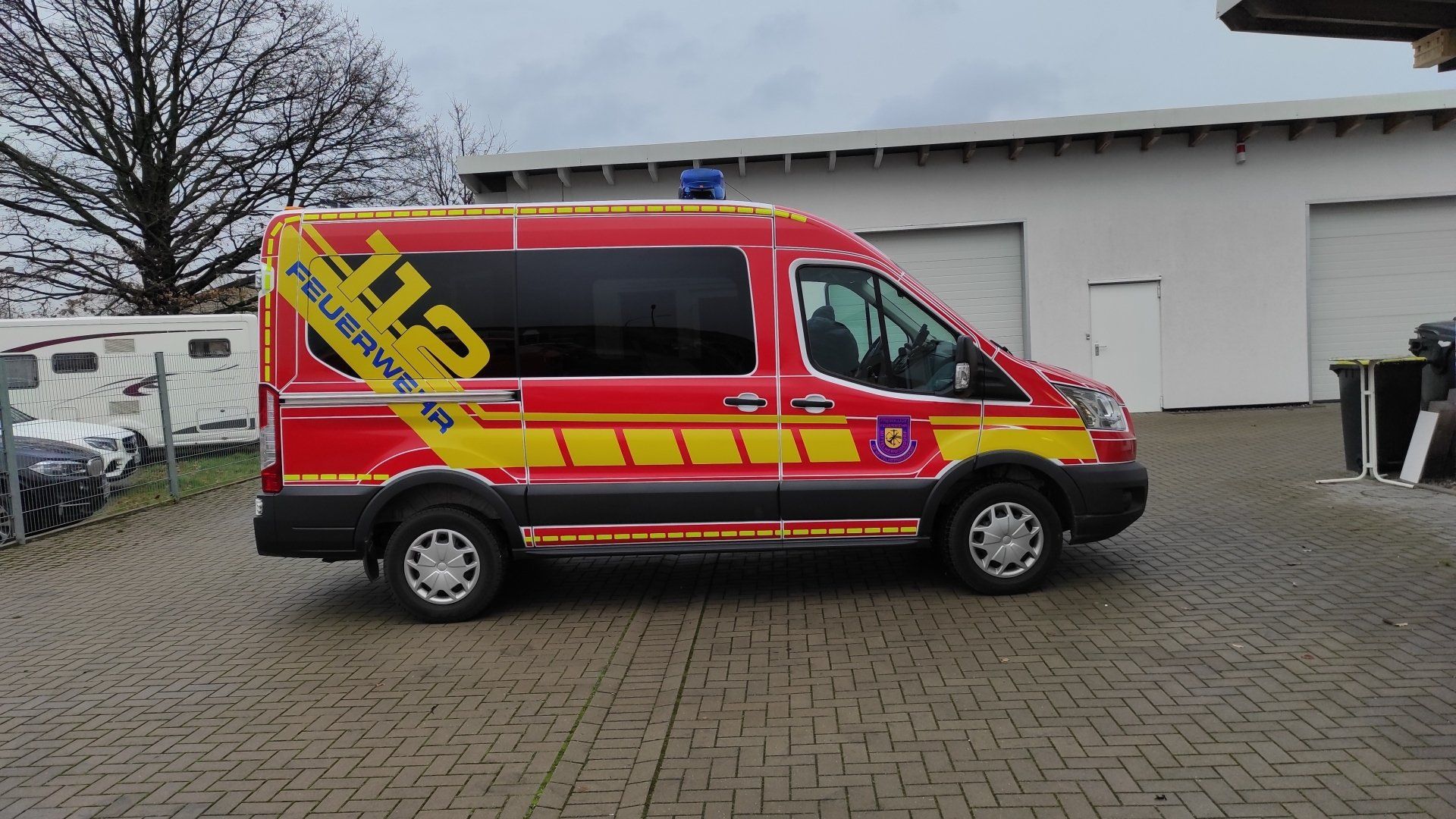 A red and yellow van is parked on a brick driveway.