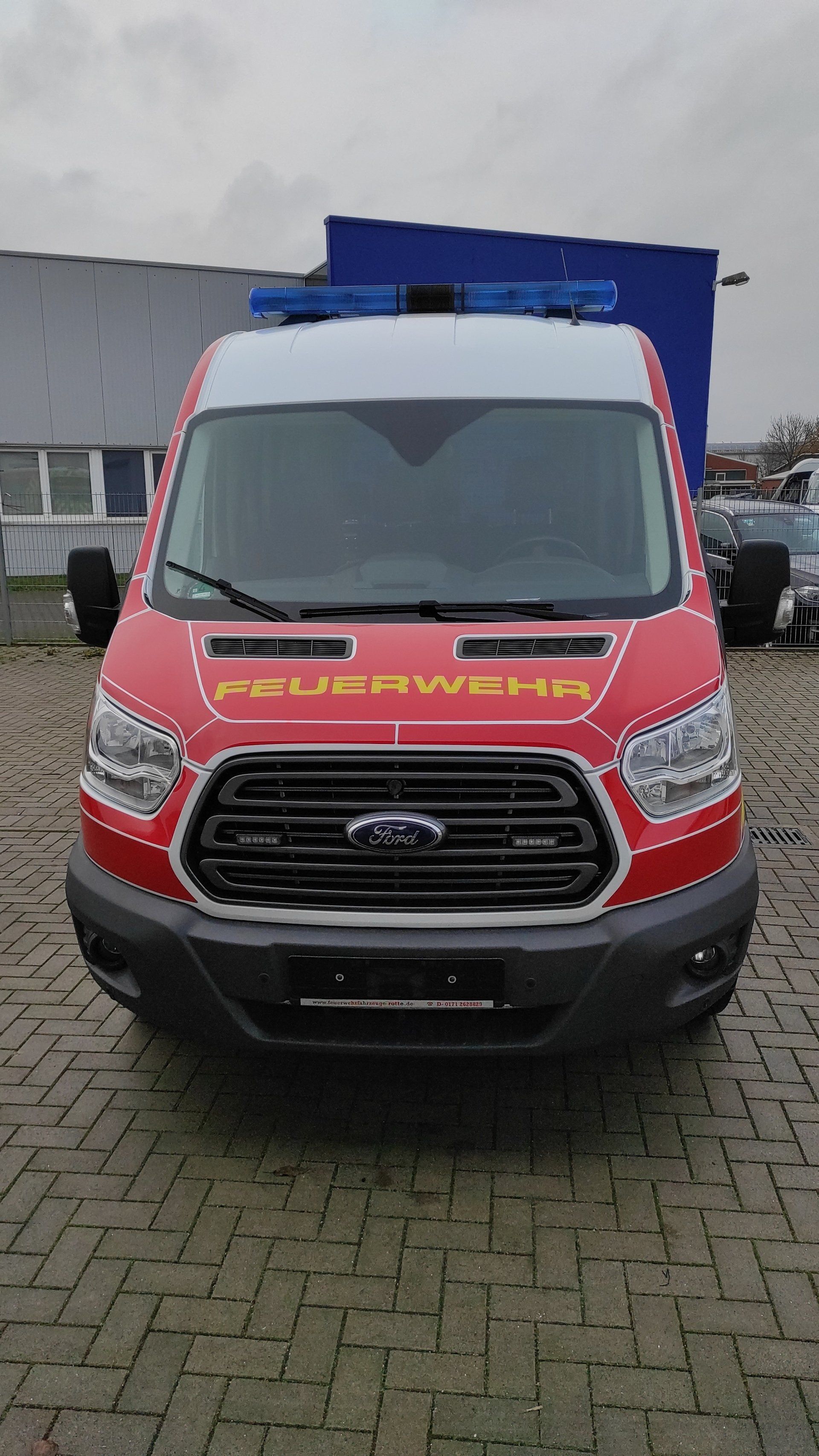 A red and white ford van is parked in a parking lot.