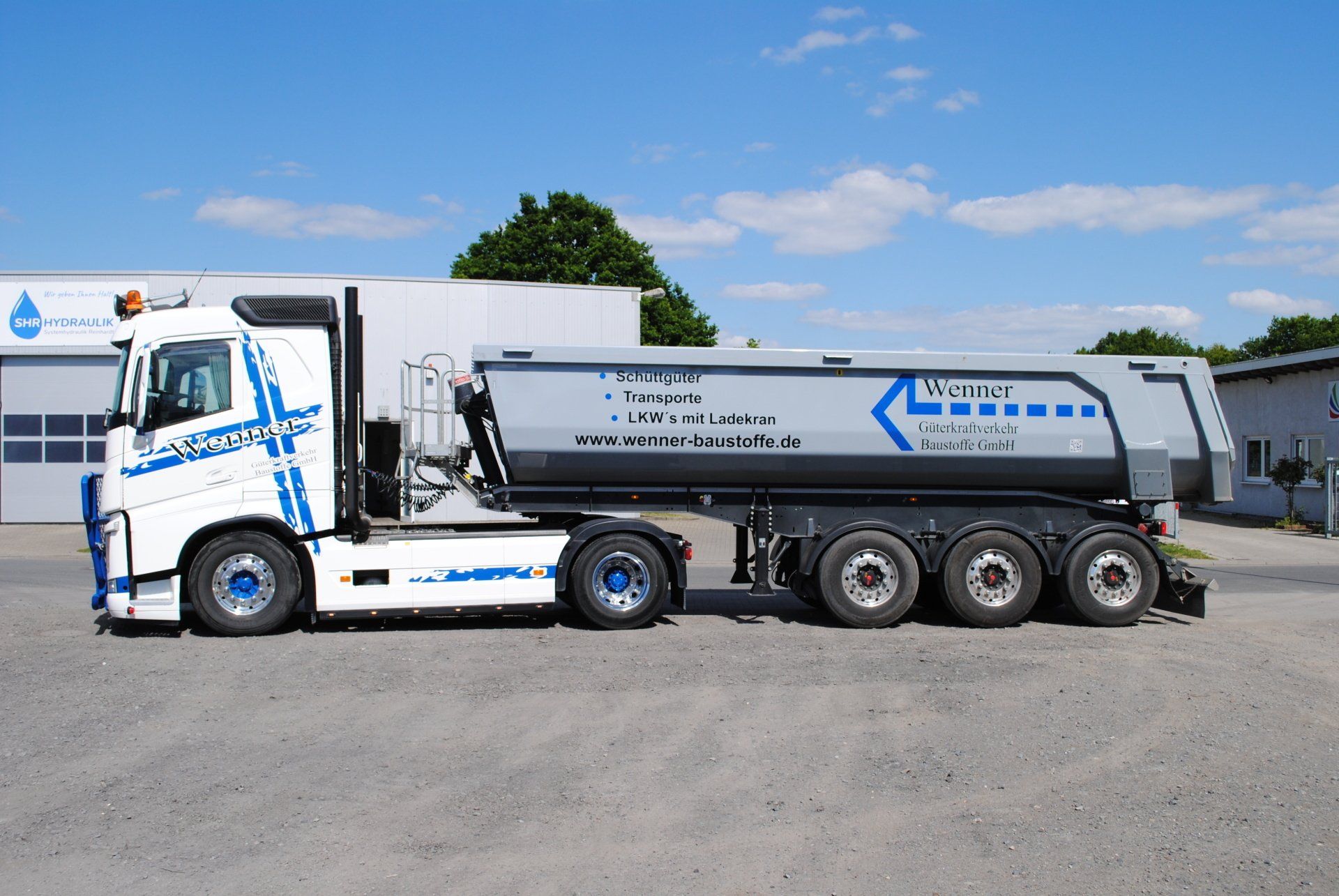 A white and blue dump truck is parked in front of a building