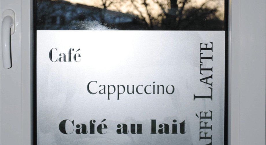 A sign on a window that says cafe cappuccino cafe au lait
