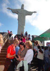 Um grupo de pessoas está em pé em frente a uma estátua de jesus