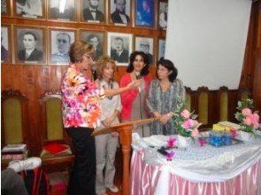 Um grupo de mulheres está de pé ao redor de um pódio em frente a uma parede de fotos.