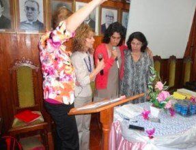 Uma mulher está em um pódio fazendo um discurso para um grupo de mulheres.