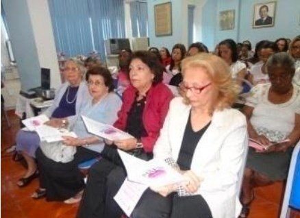 Um grupo de mulheres está sentado em uma sala segurando papéis.