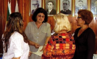 Um grupo de mulheres está em pé em frente a uma parede com fotos de homens