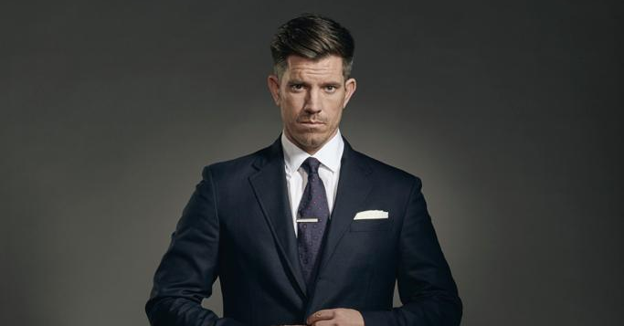A man in a suit and tie is adjusting his jacket.
