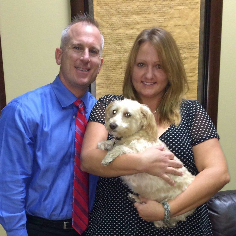 A man and a woman holding a small white dog