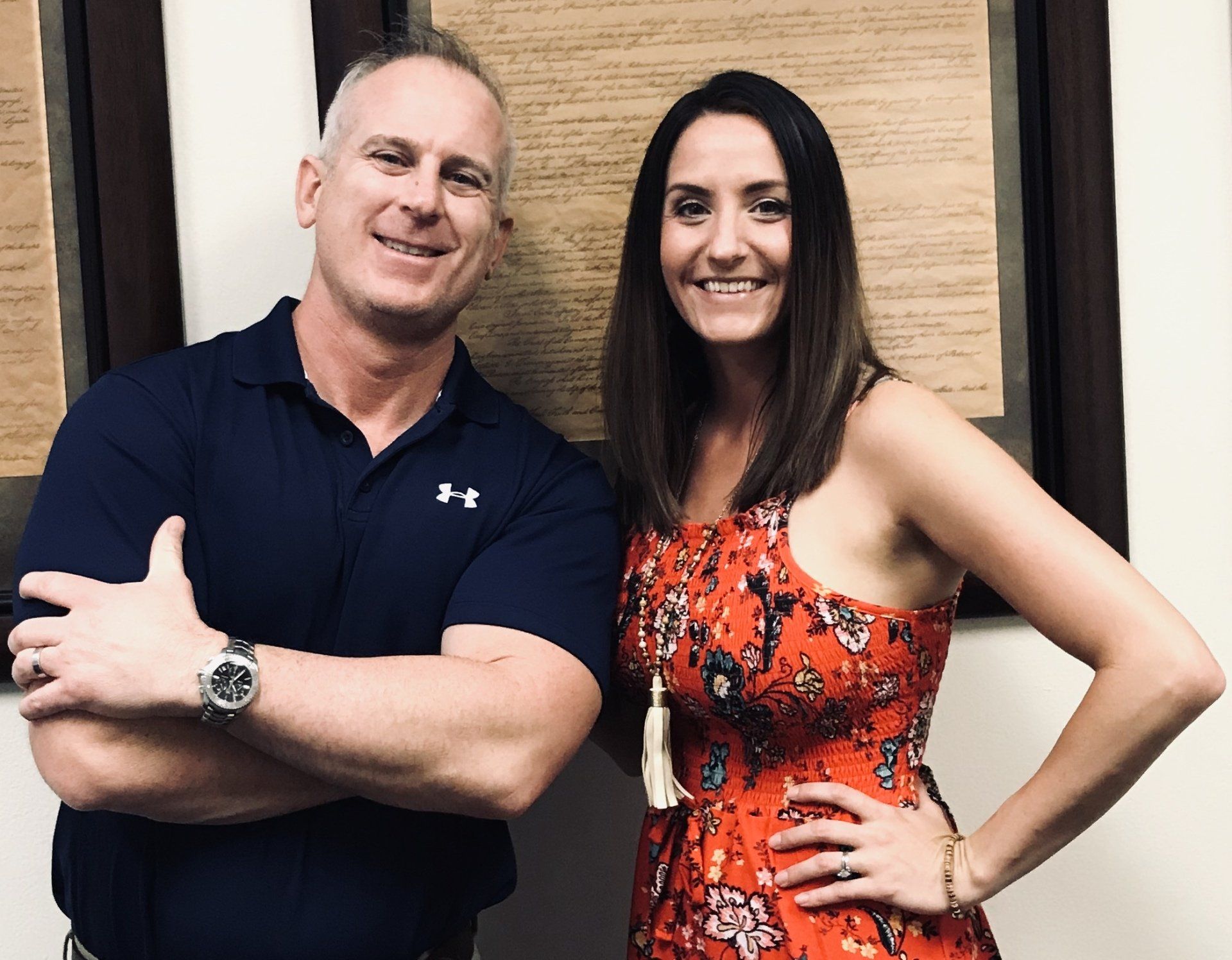 A man and a woman are posing for a picture with their arms crossed.