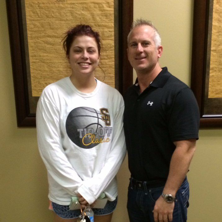 A man and a woman are posing for a picture and the woman is wearing a shirt that says tip off classics