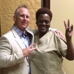 A man and a woman are posing for a picture and the woman is giving a peace sign