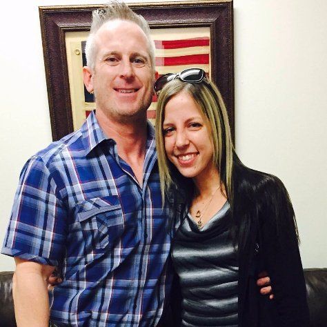 A man and woman are posing for a picture in front of an american flag