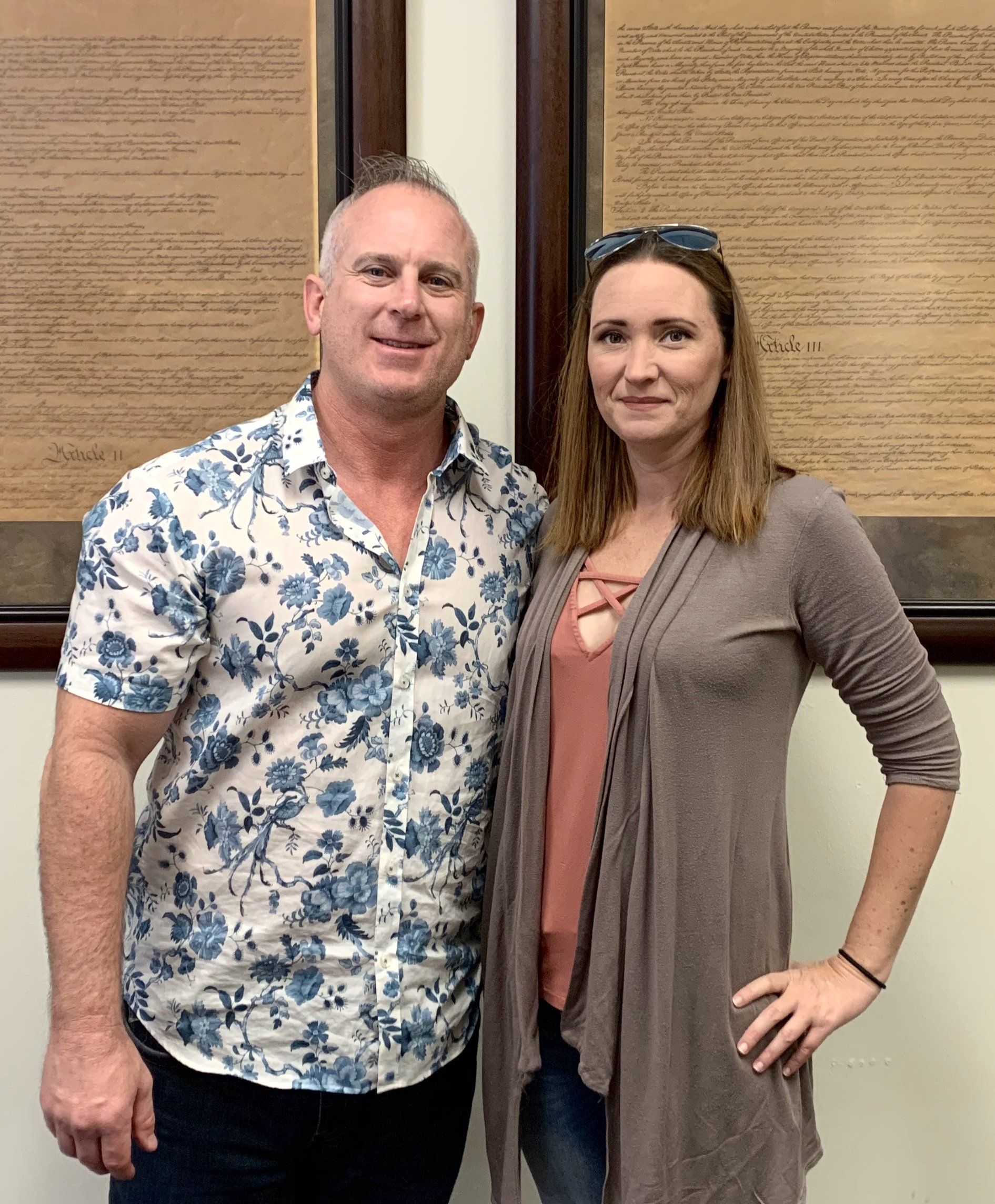 A man and a woman are standing next to each other in front of a wall.