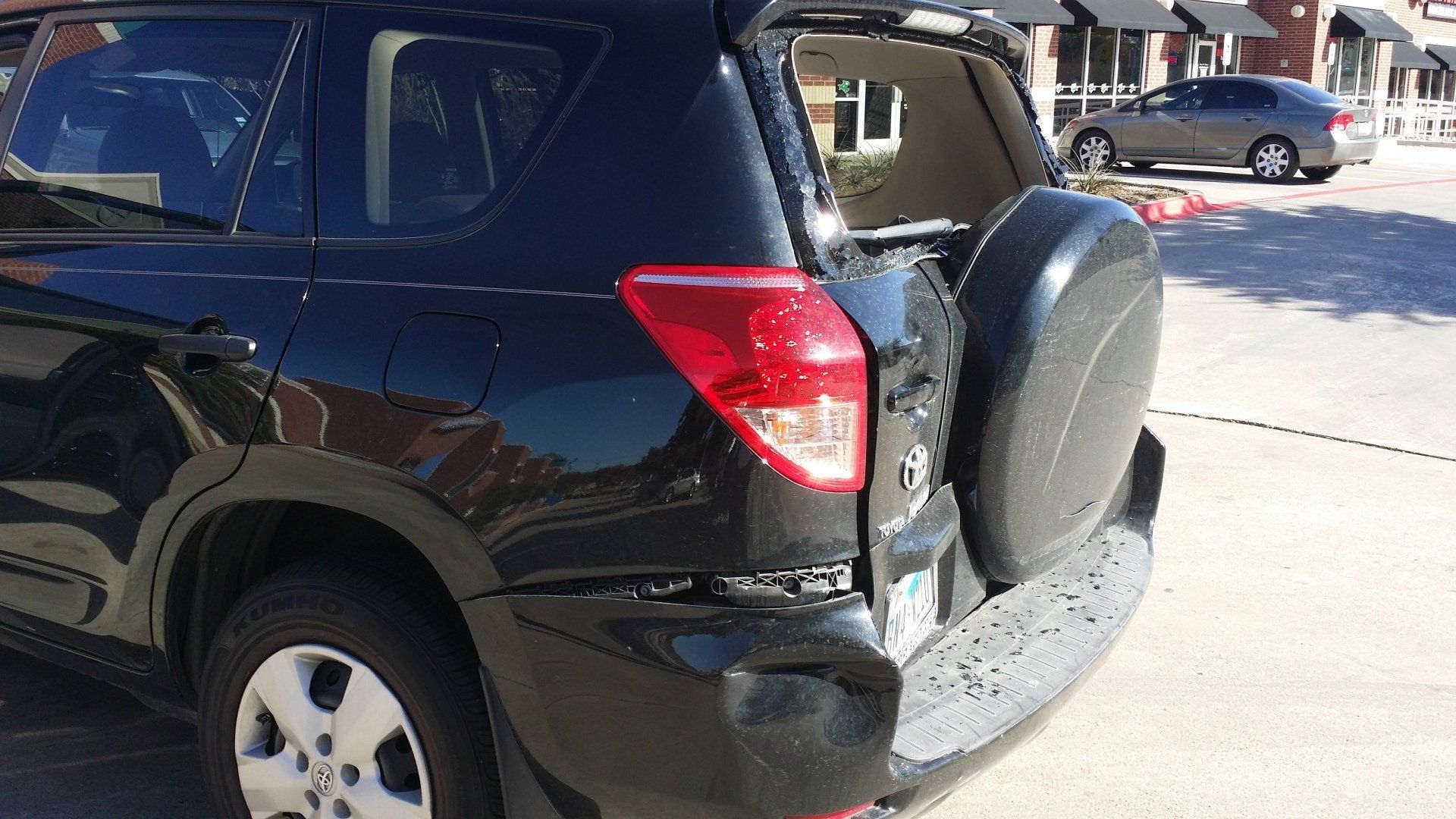 A black suv with the trunk open is parked in a parking lot