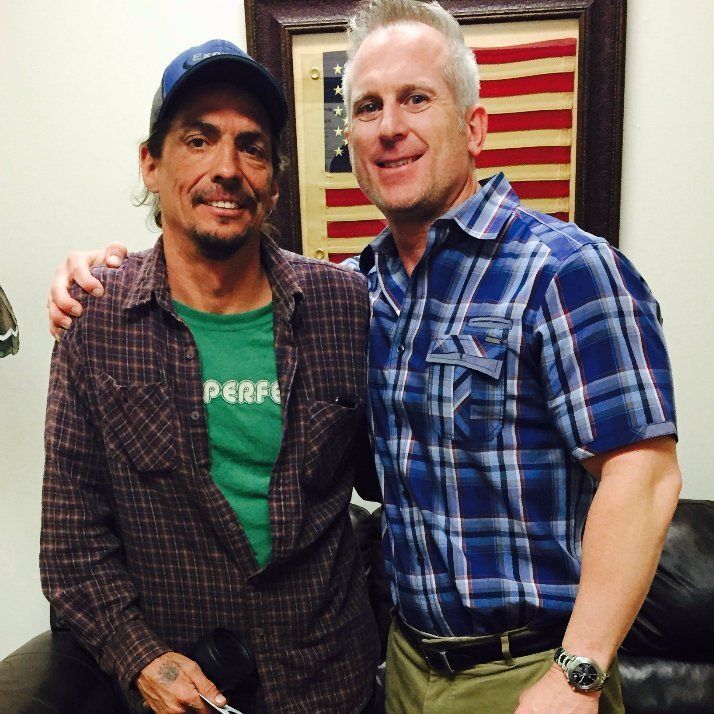 Two men posing for a picture with one wearing a green shirt that says perf