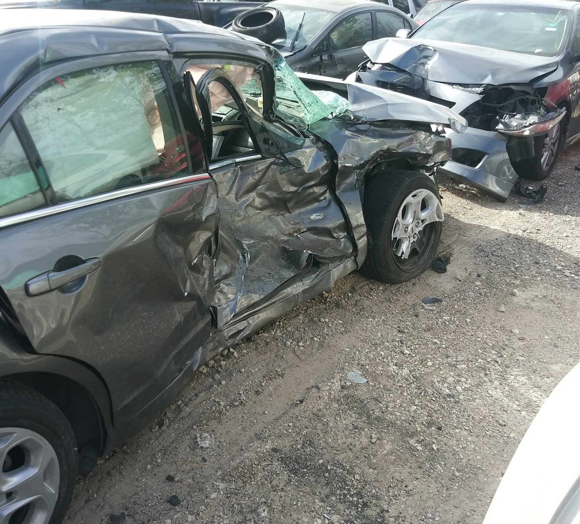 A damaged car is parked next to another car
