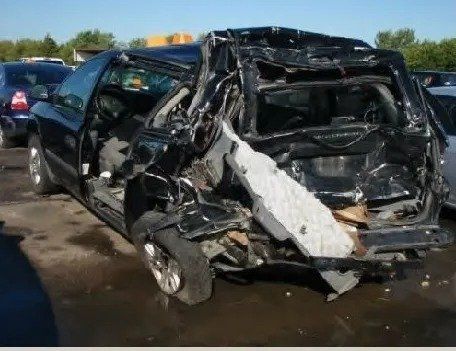 A wrecked car is sitting in a parking lot.