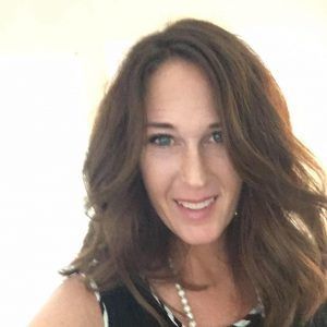 A woman with long brown hair is smiling for the camera.