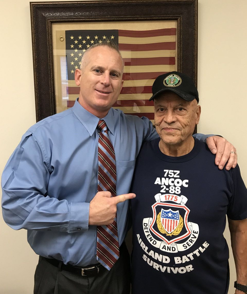 Two men posing for a picture with one wearing a shirt that says 752 ancoc 2-28