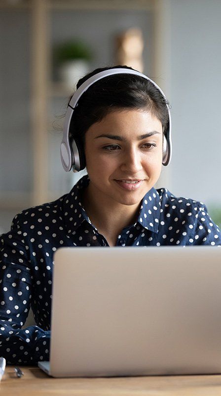 young woman on laptop wearing headphones