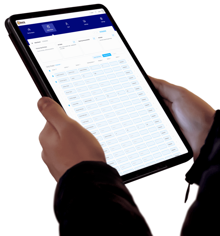 Hands holding a digital tablet displaying a dense data table or spreadsheet application with a blue navigation bar.