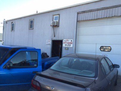 A blue truck and a car are parked in front of a building