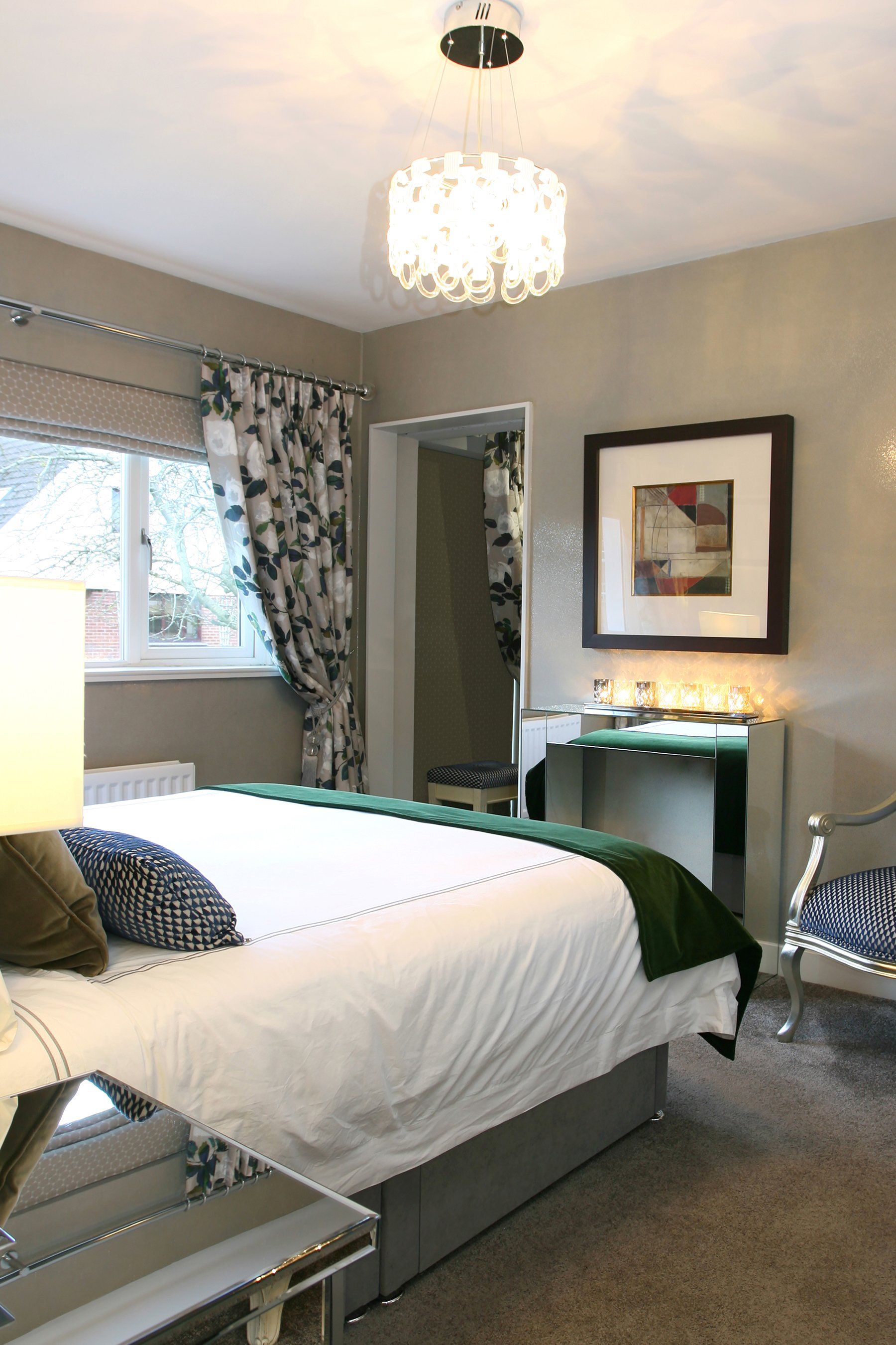 A bedroom with a king size bed , chair , table and mirror.
