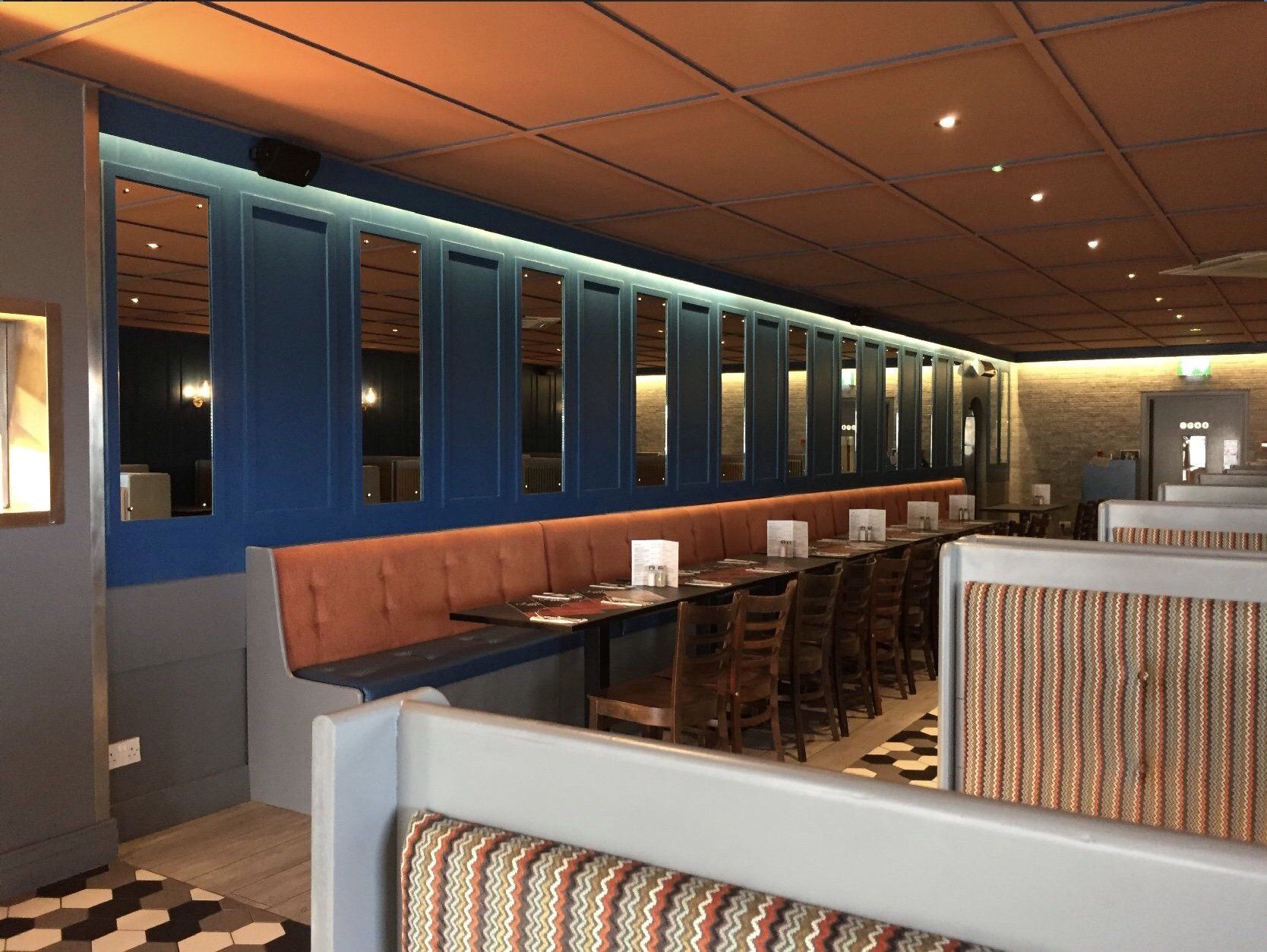A restaurant with tables and chairs and a long bench.