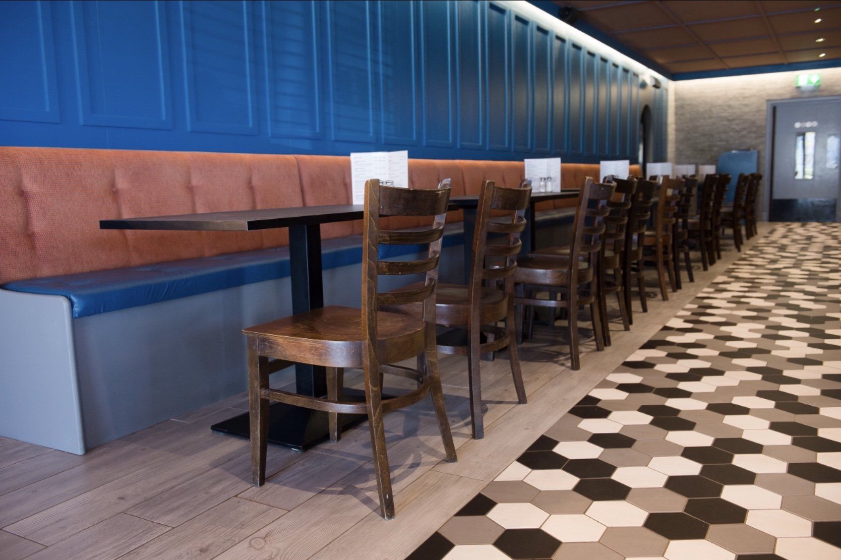 A long hallway with tables and chairs in a restaurant.
