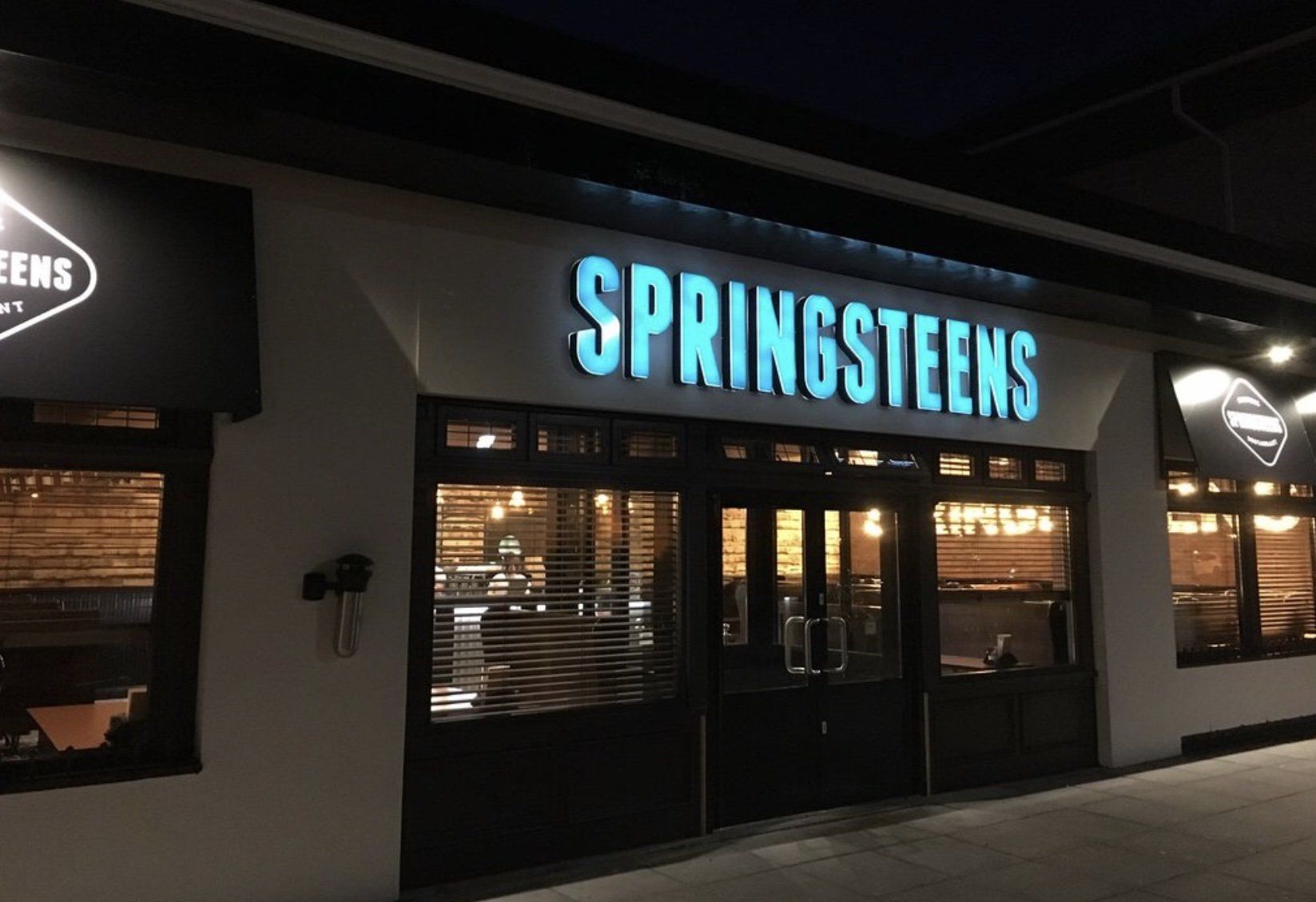 A restaurant called springsteens is lit up at night