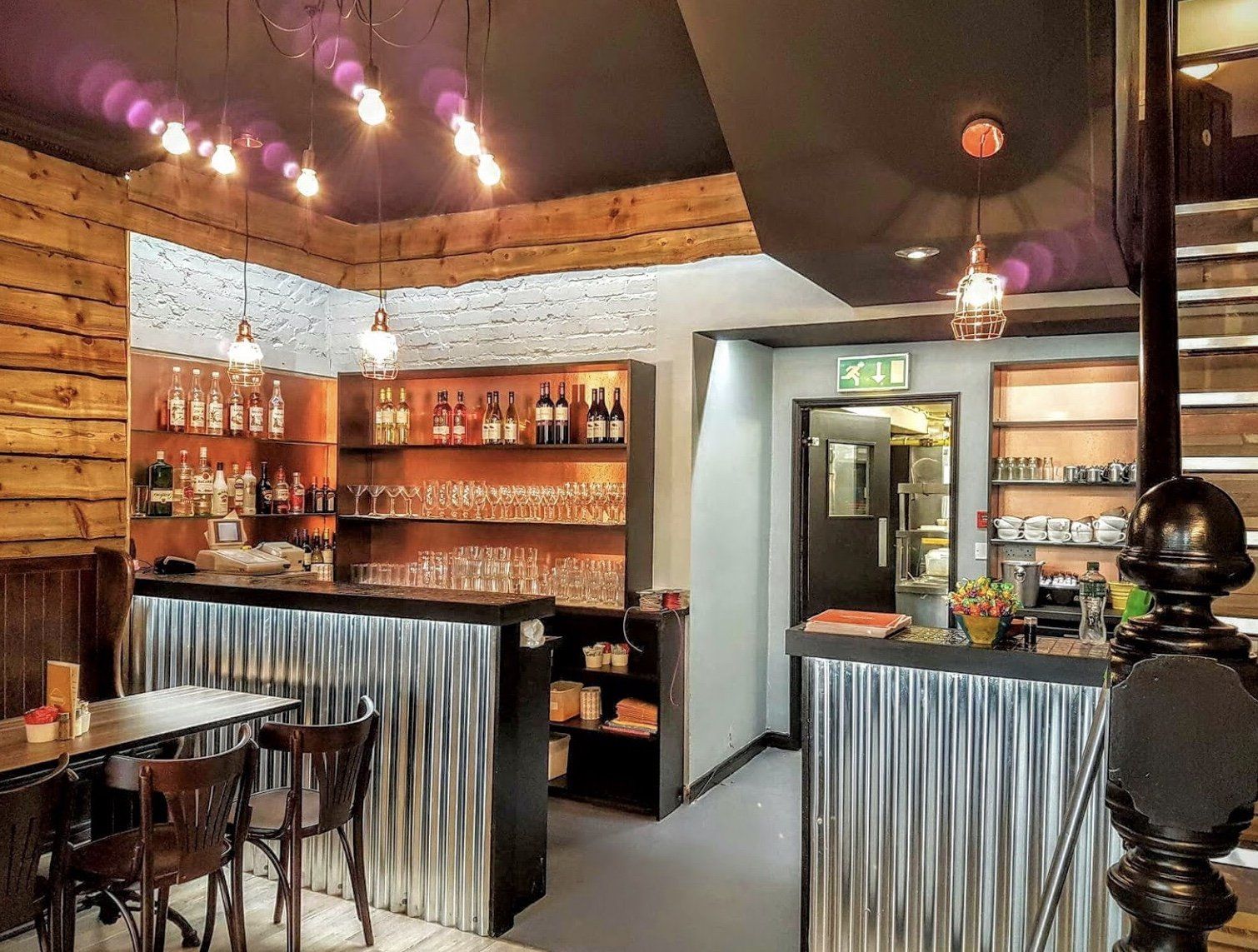 A restaurant with a bar and tables and chairs.