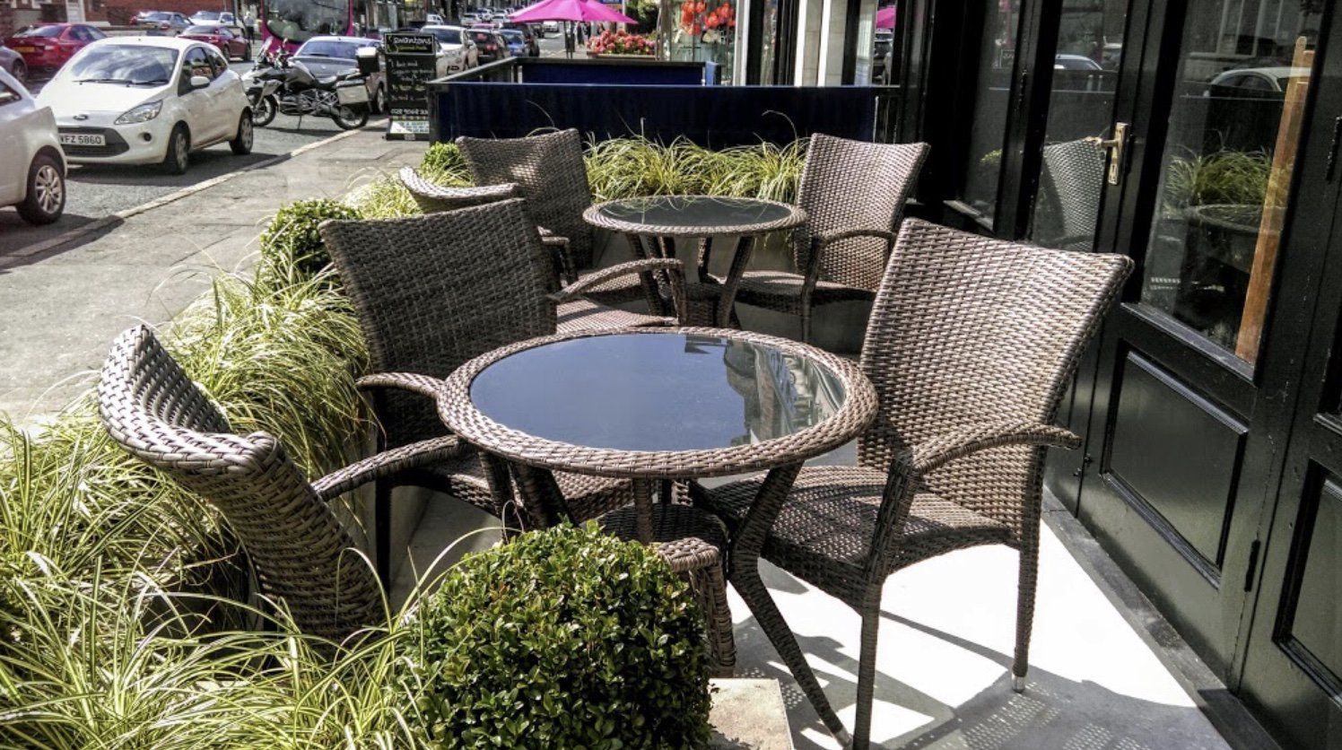 A row of wicker tables and chairs outside of a building.