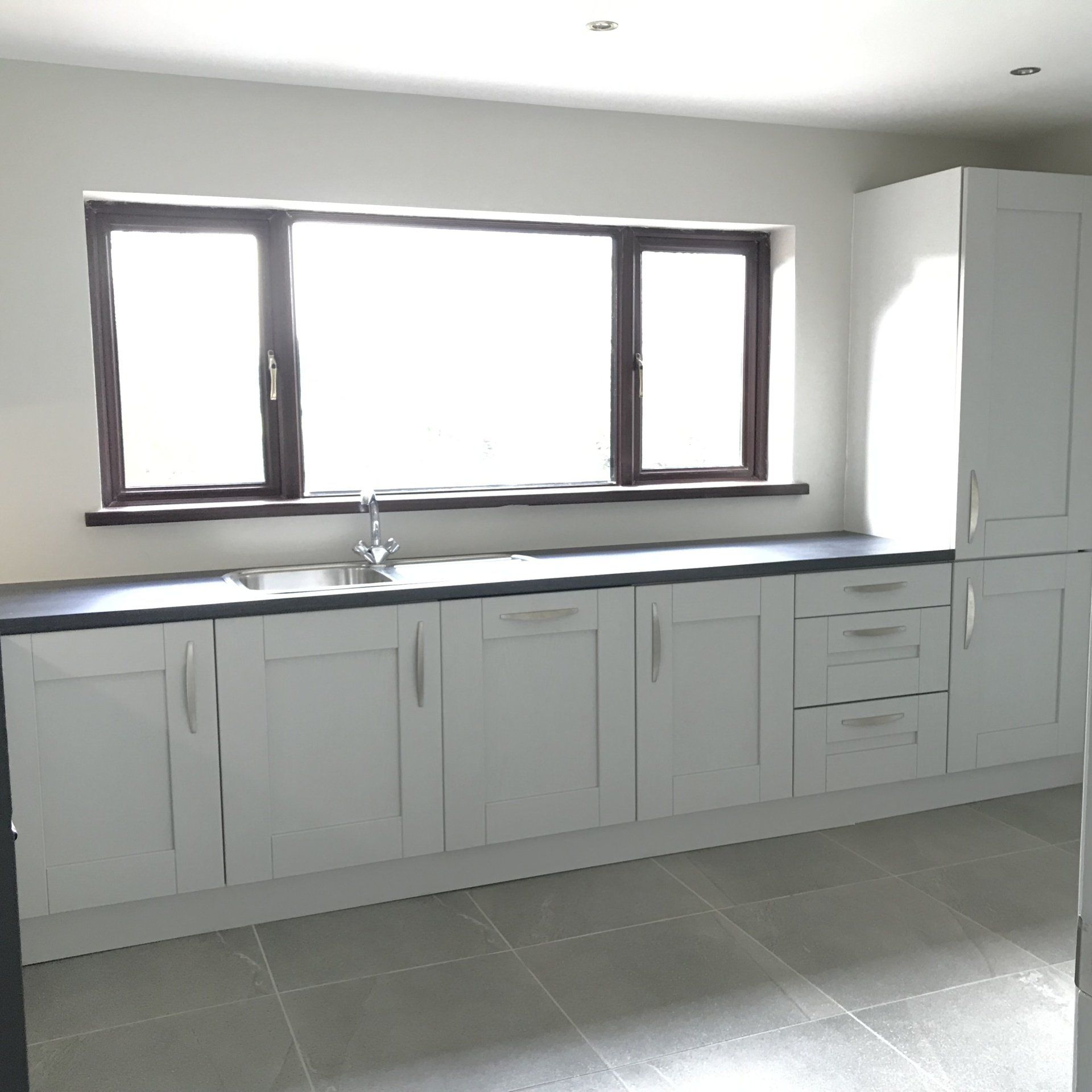 A kitchen with white cabinets and a window