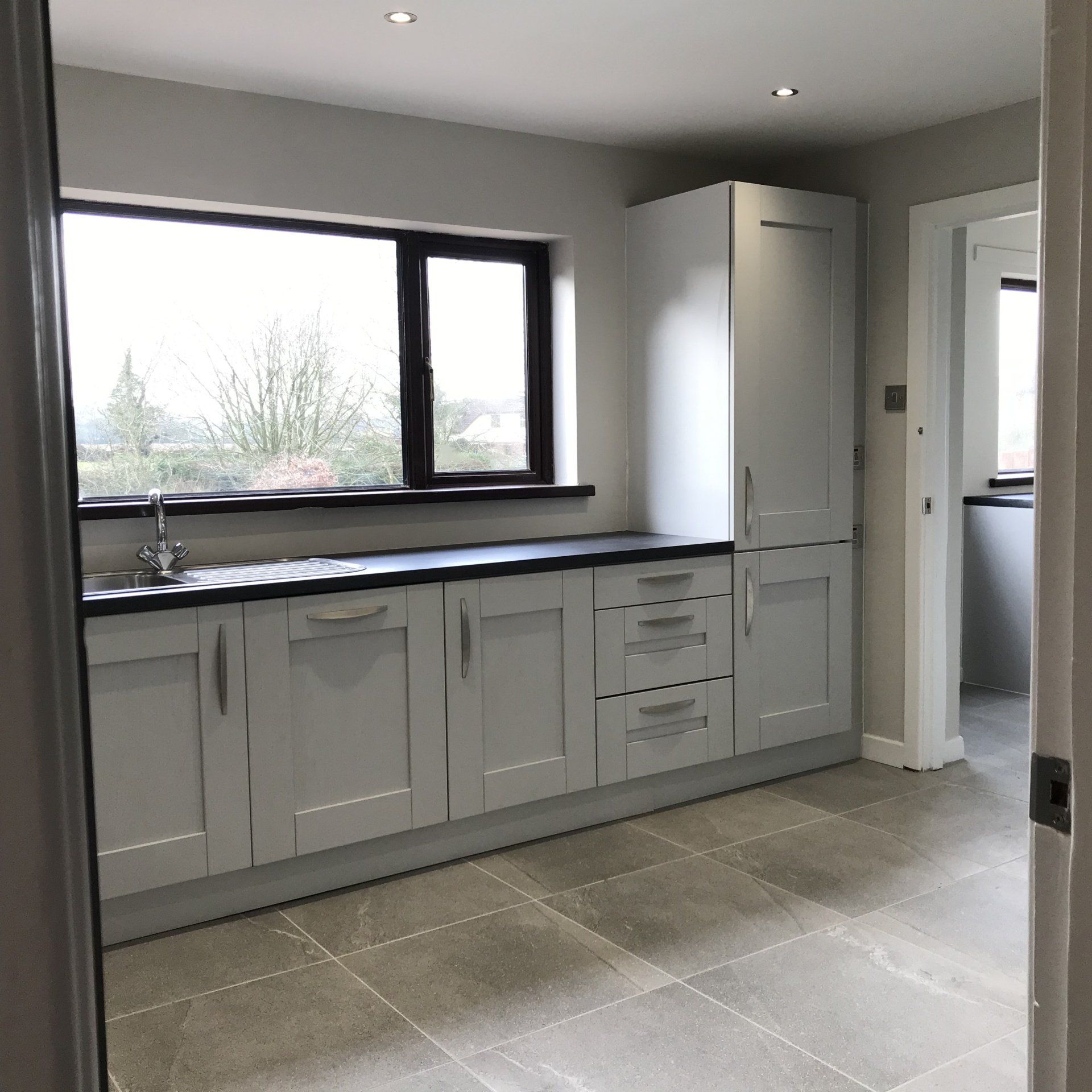 A kitchen with white cabinets and a window