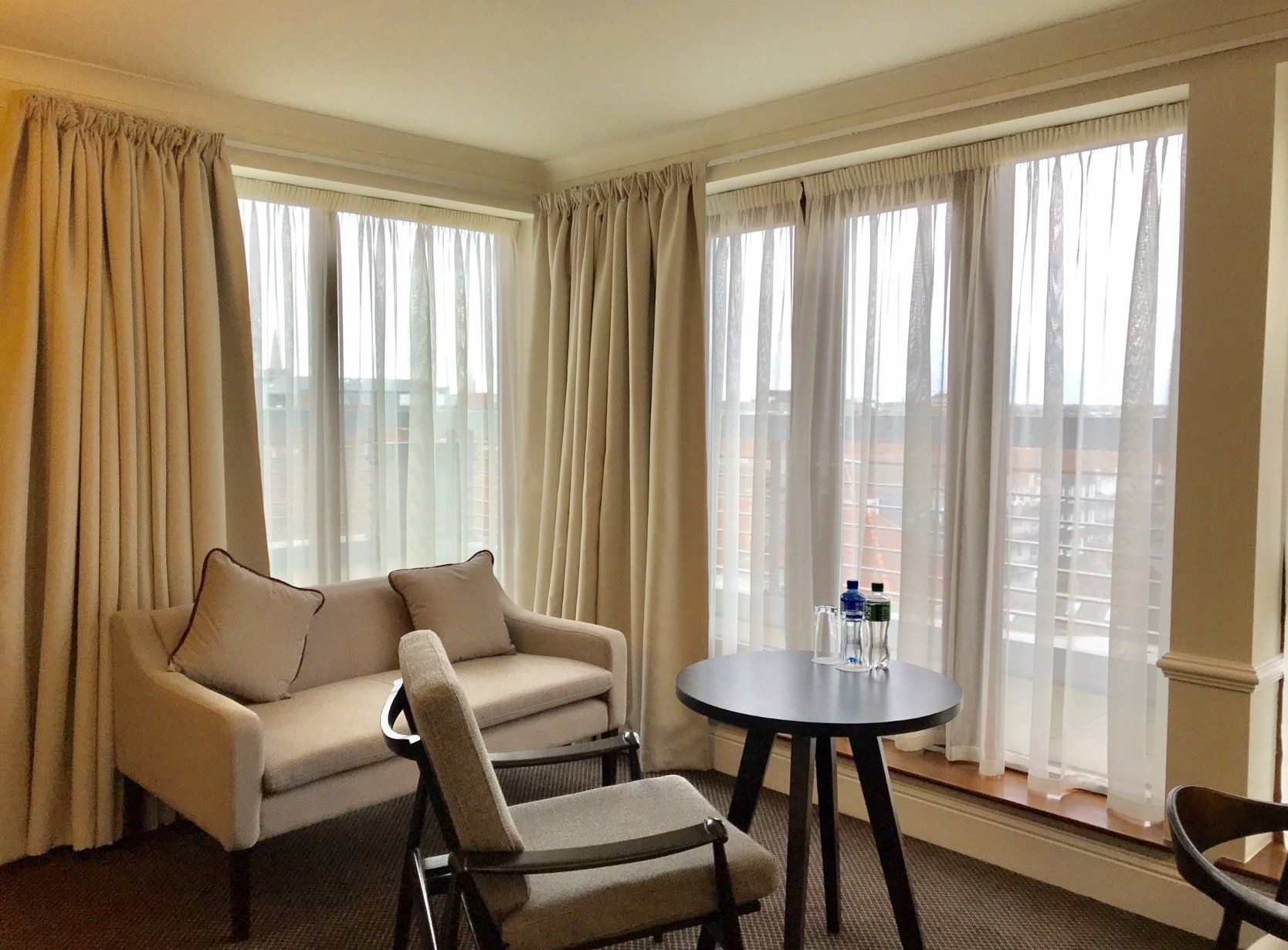 A hotel room with a couch , chairs , and a table.