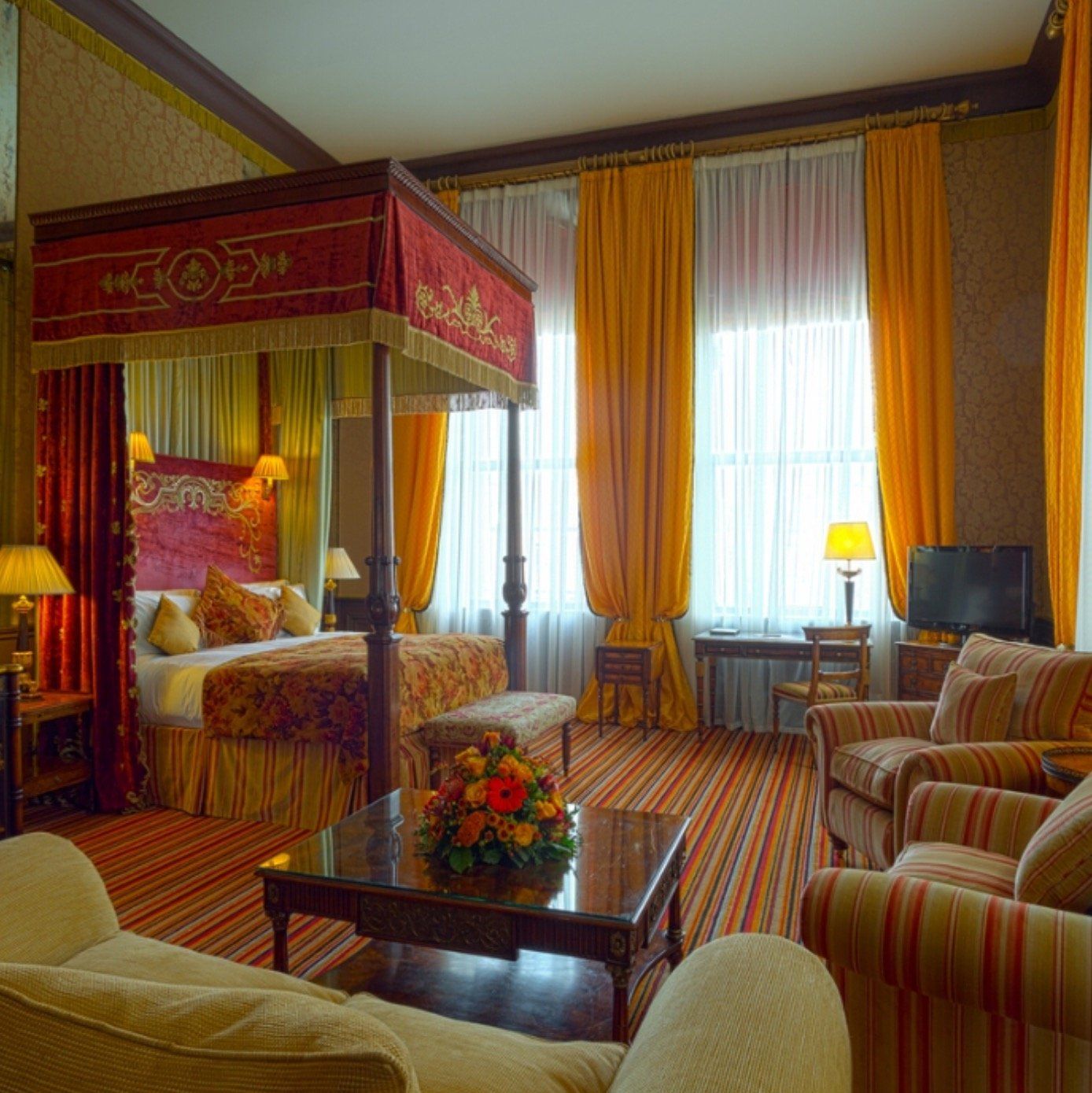 A hotel room with a canopy bed and chairs
