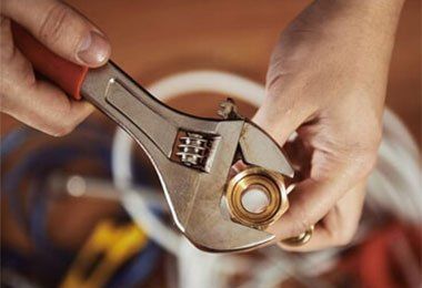 A person is holding an adjustable wrench over a nut.