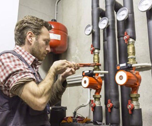 A man is working on a pipe with a wrench.