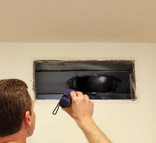 Worker checking air vent with flash light