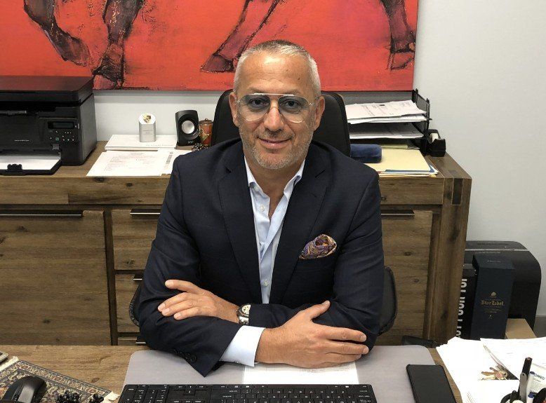 A man in a suit is sitting at a desk with his arms crossed