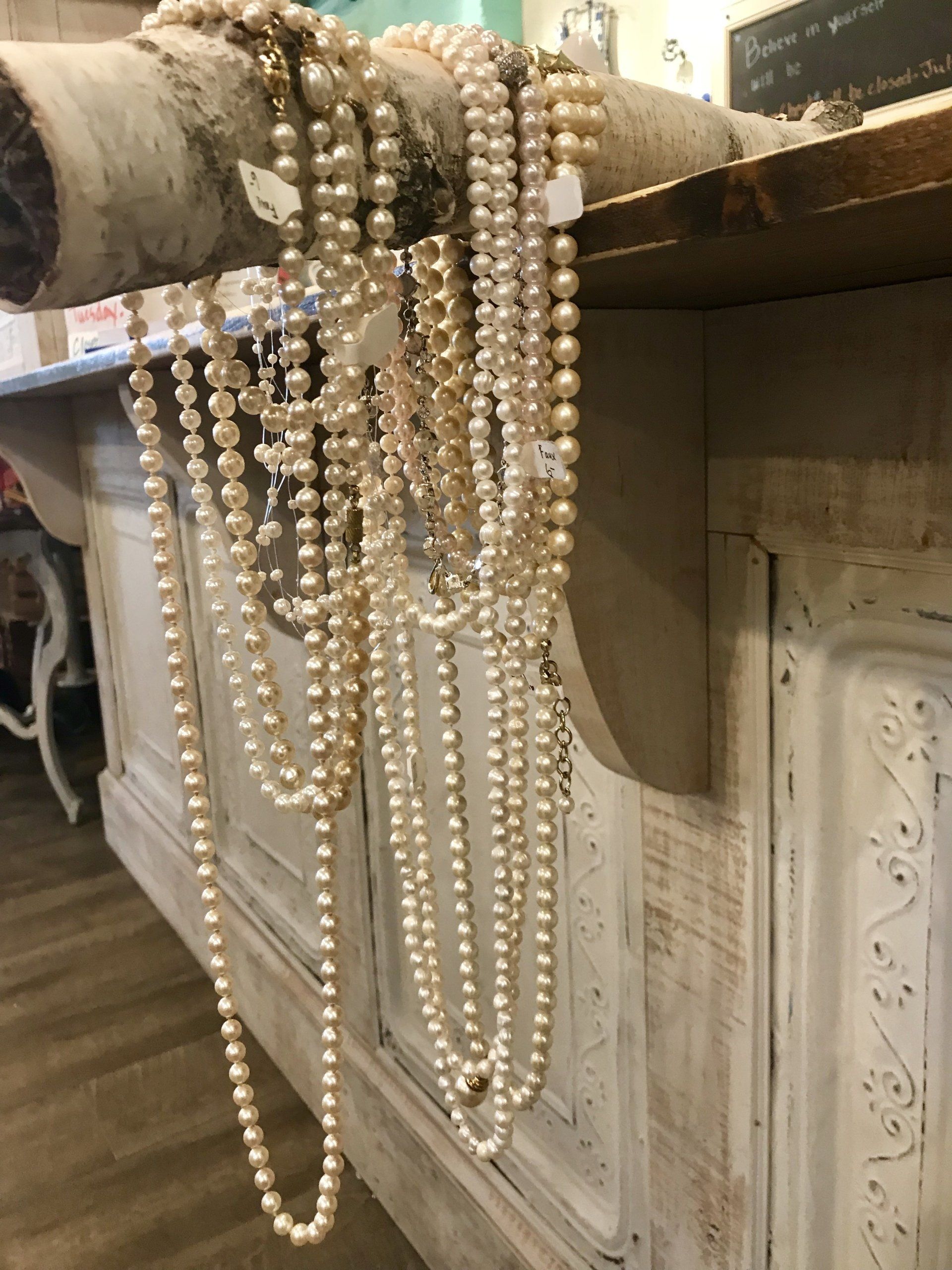 A bunch of pearl necklaces are sitting on a counter.