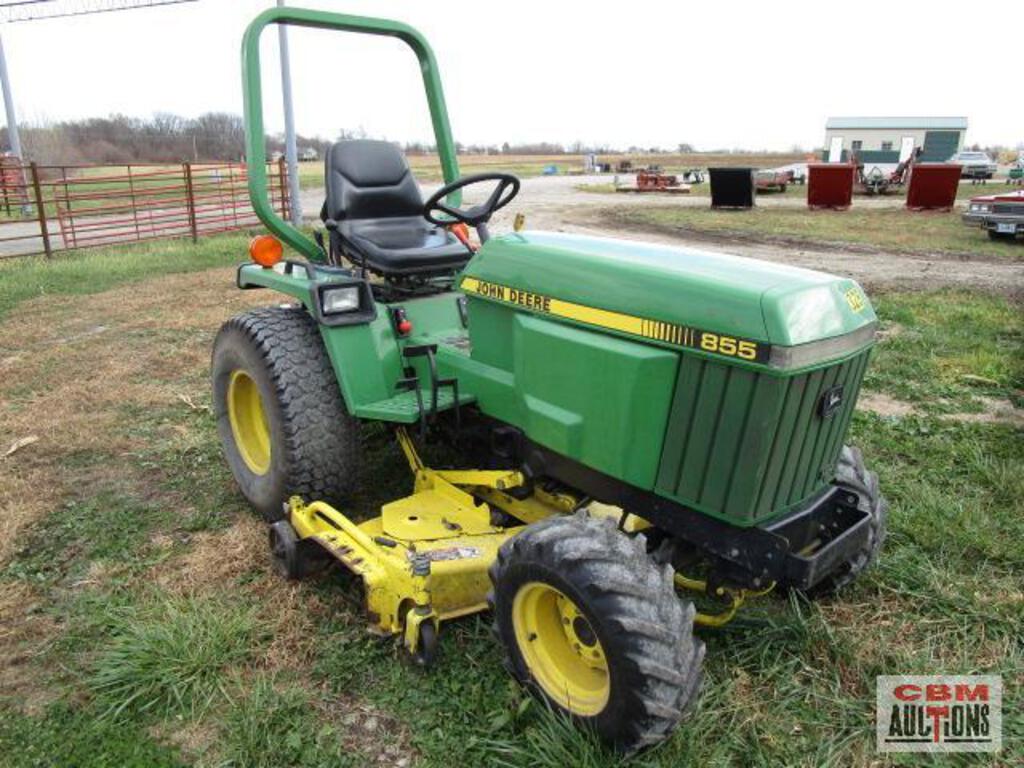 A green and yellow john deere tractor is parked in a grassy field.