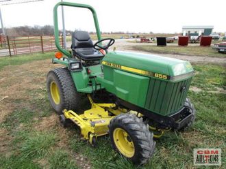 A green and yellow john deere tractor is parked in a grassy field.