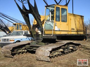 A large yellow crane is parked next to a ford truck