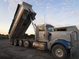 A kenworth dump truck is parked in a gravel lot