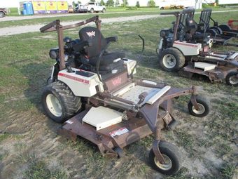 A brown and white lawn mower is parked in the grass