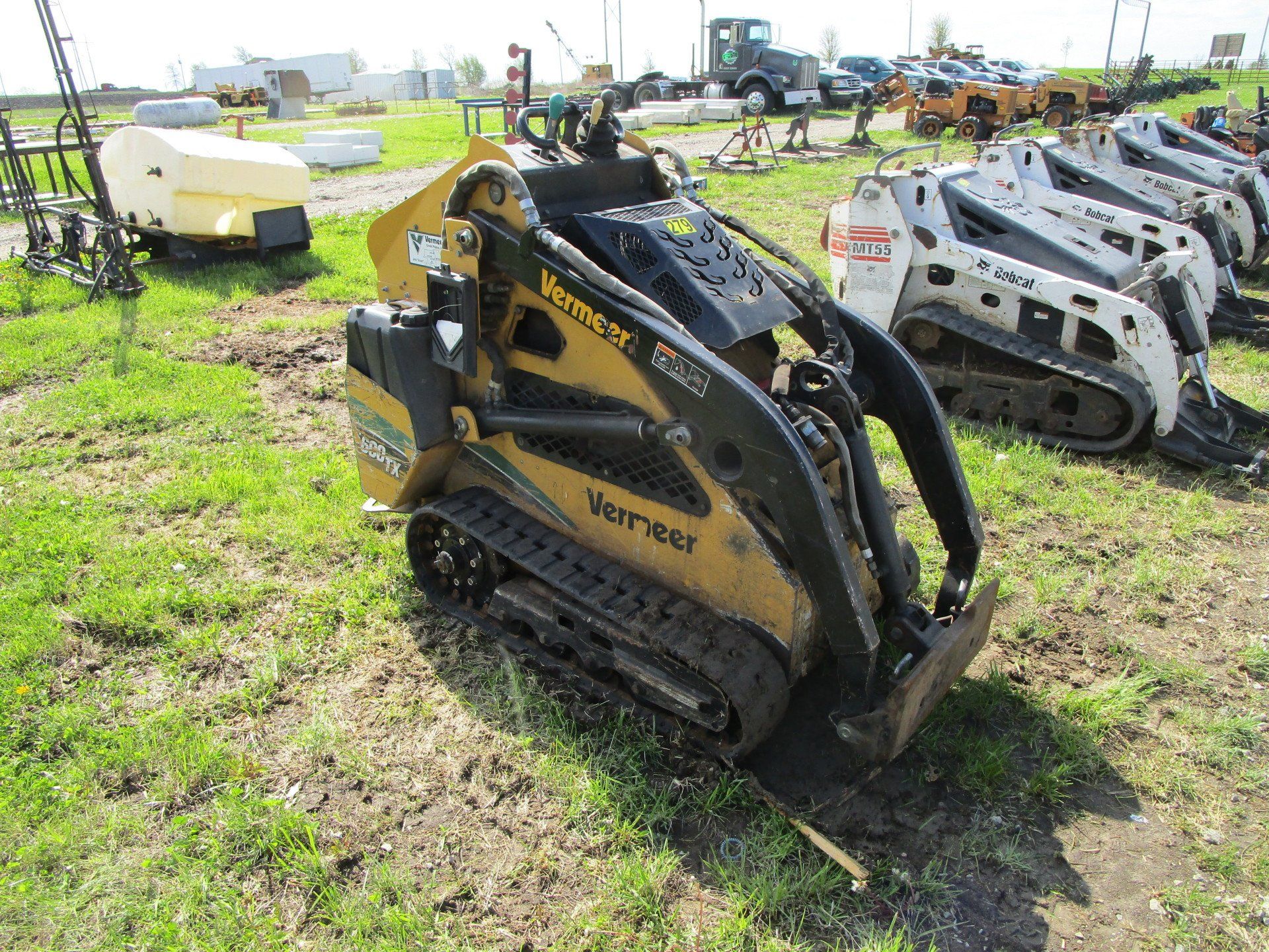 A small yellow and black tractor is parked in a grassy field.