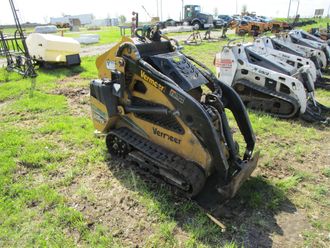 A small yellow and black tractor is parked in a grassy field.
